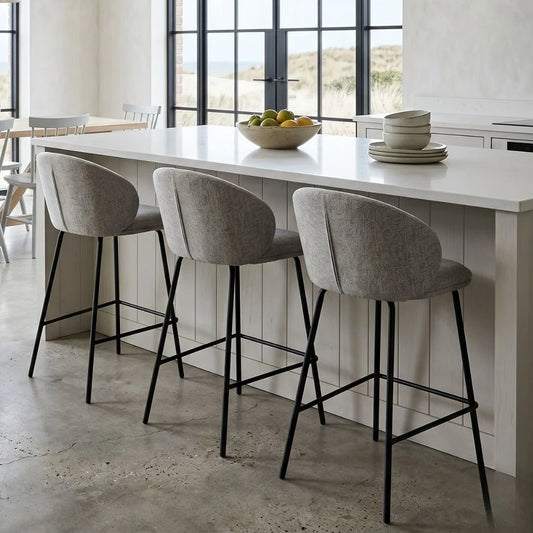 Modern kitchen with a white island, gray bar stools, and a view of the outdoors.