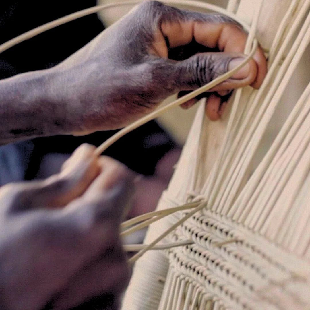 Close-up of hands weaving with natural fibers.
