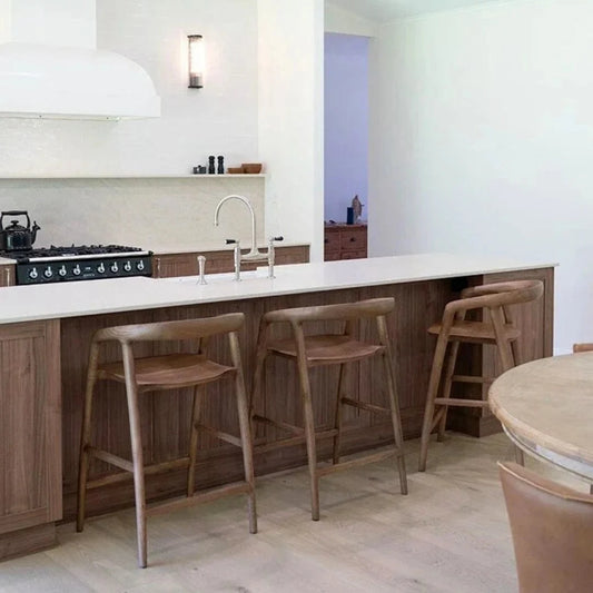 Modern kitchen with wooden bar stools and a white countertop.
