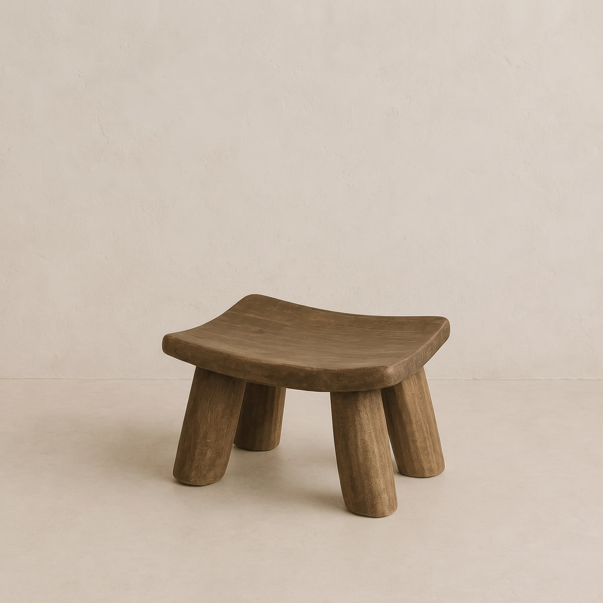 A small rustic wooden stool with a curved seat and four chunky legs, shown against a neutral beige textured wall and floor.