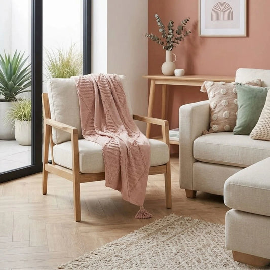 Cozy living room with a chair draped with Sun Republic Blush pink throw blanket and a couch with decorative pillows.