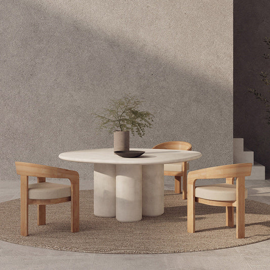 Dining area with a round marble table and wooden chairs against a gray wall.