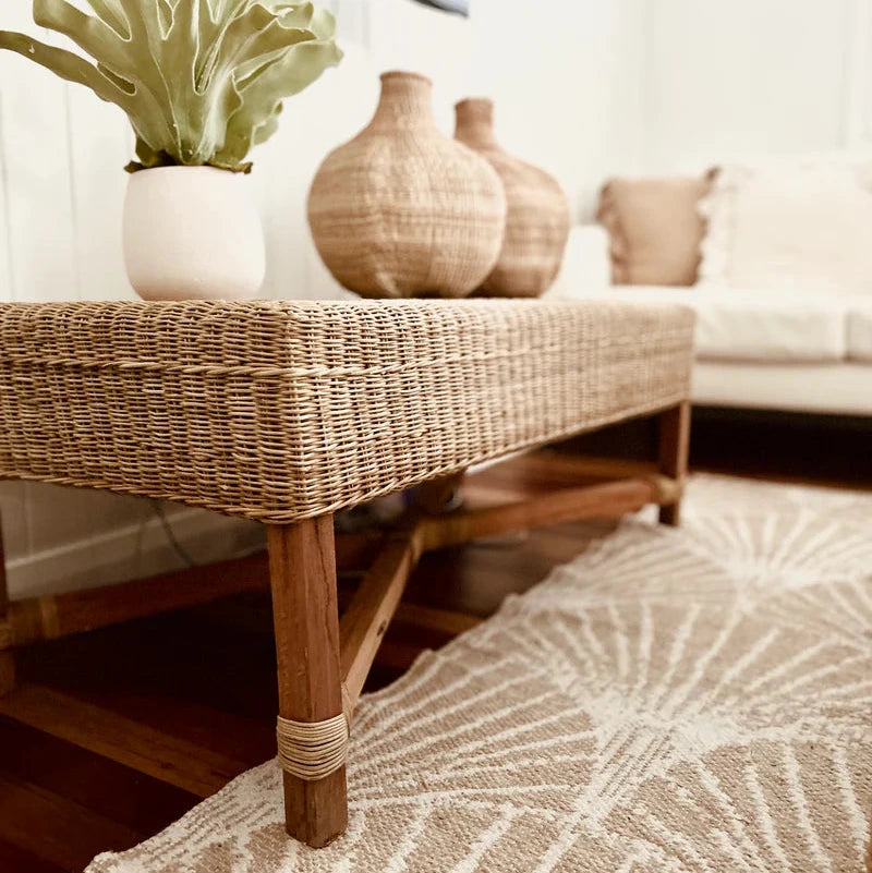 Wicker coffee table with decorative vases and a plant in a living room setting.