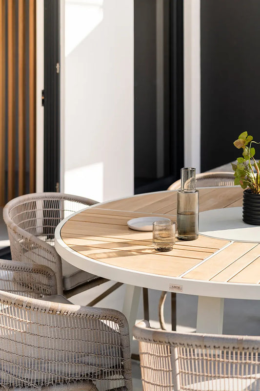 Outdoor dining area with wooden table and wicker chairs on a patio.