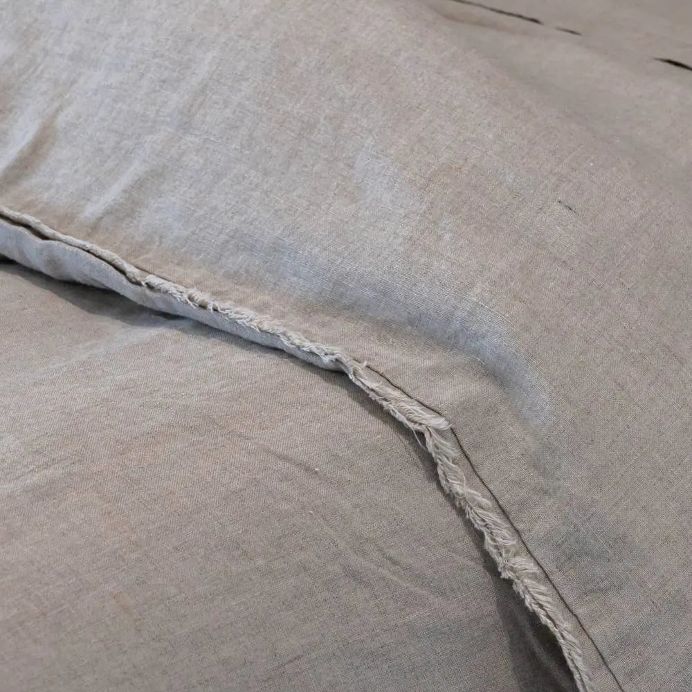 Close-up of beige linen pillowcases with frayed edges.