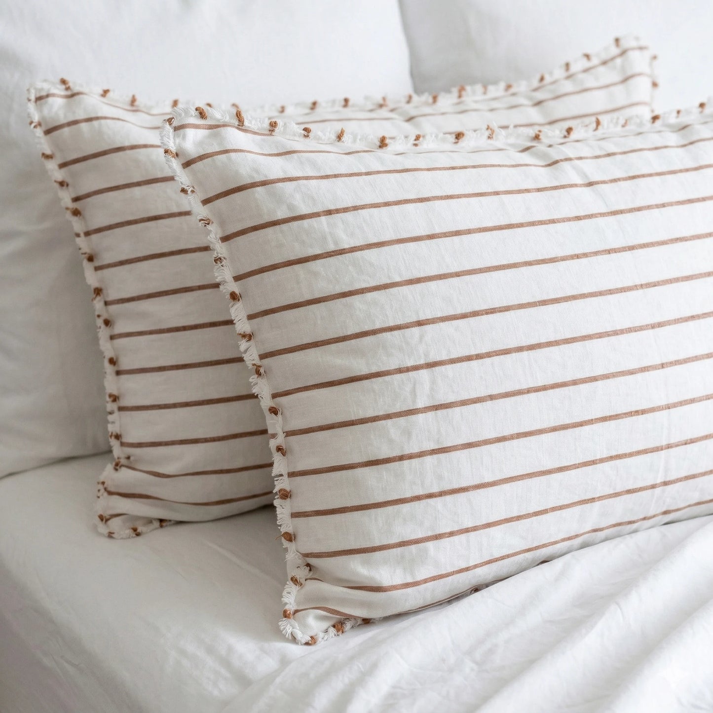 Two striped pillows on a white bed