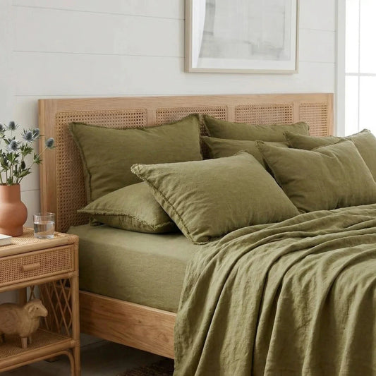 Bedroom with a wooden bed and green bedding, side table with decor items.