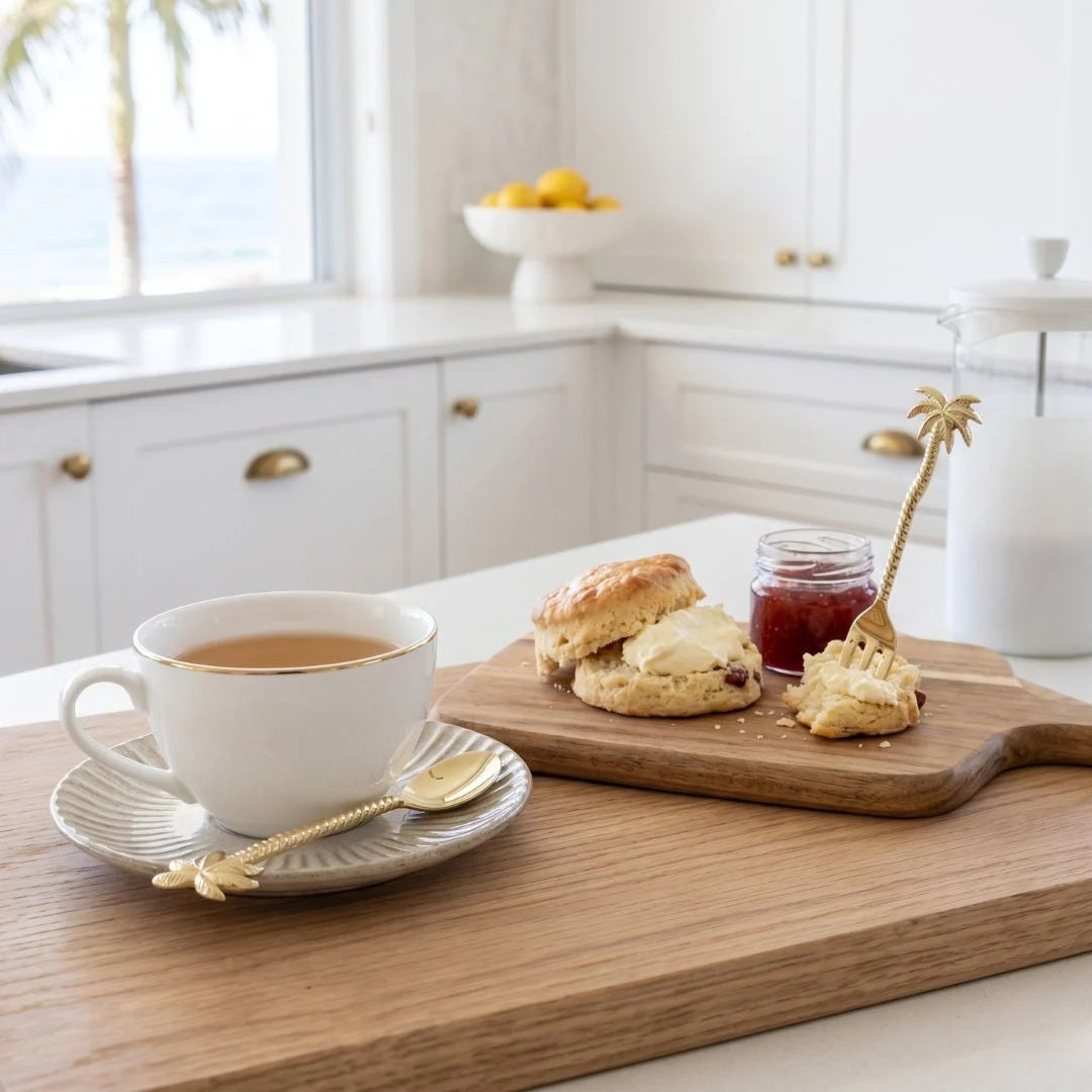 Tea cup with scones and jam on a wooden board in a kitchen setting