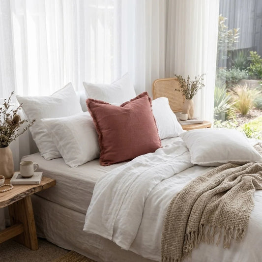 Hand loomed pink peony coloured cushion in a light and bright bedroom
