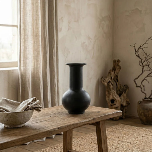 Black vase on a wooden bench with a neutral background