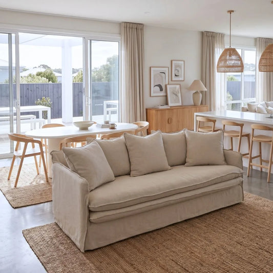 Beige sofa in a living room with a dining area in the background
