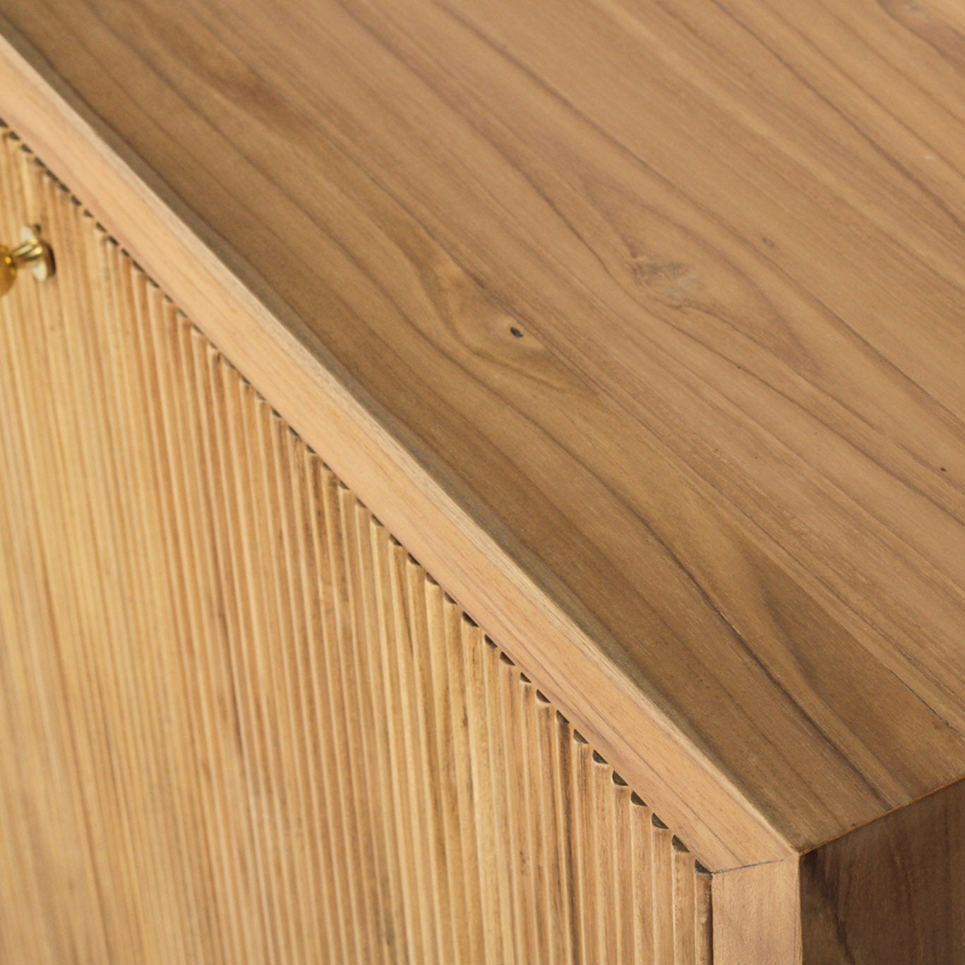 Close-up of a wooden cabinet with a focus on the top surface and side panel.