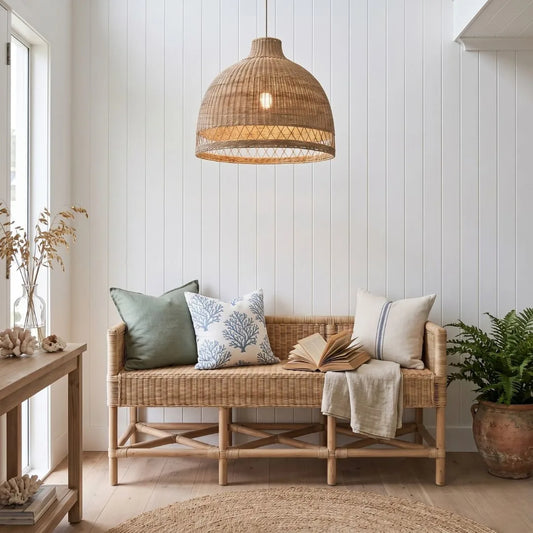 Nautical-themed room with a wicker bench, pillows, and a book under a woven pendant light.