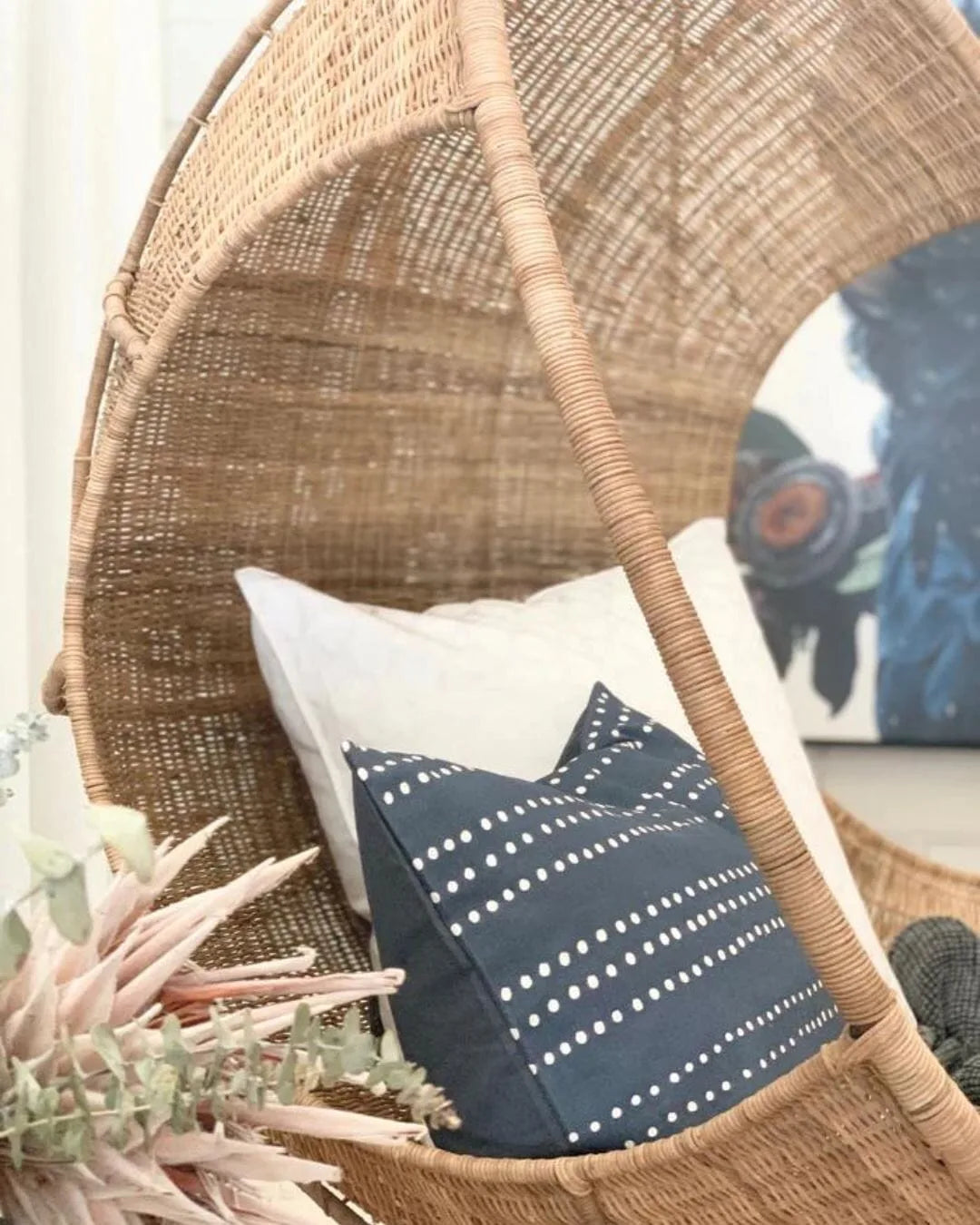 Wicker chair with a decorative pillow featuring a cat design.