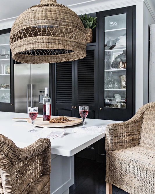 Kitchen with woven cane stools, a white table, and wine glasses.