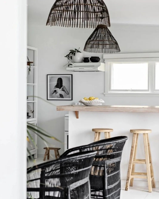 Modern kitchen with wooden table, black chairs, and wicker pendant lights.
