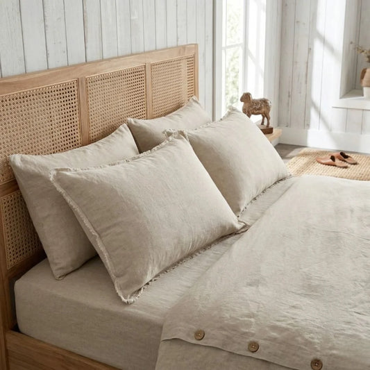 Beige bedding set on a bed with a wooden headboard in a bright room.