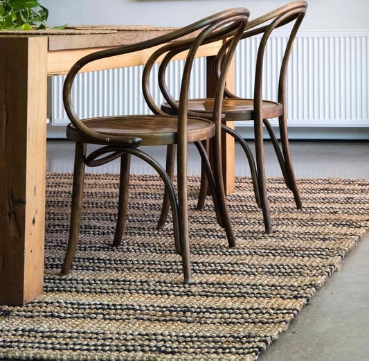 Wooden dining table with two chairs on a textured rug