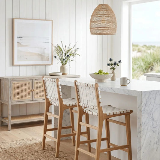 Modern kitchen with white island, wooden chairs, and wicker pendant lights.