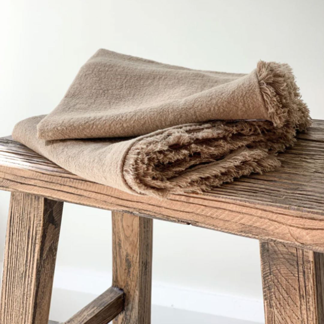 Beige blanket on a wooden stool with a white background