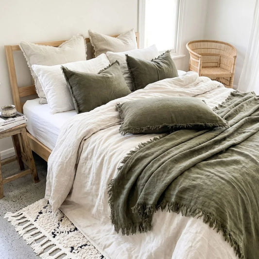 Neatly made bed with green and white bedding in a bright bedroom.