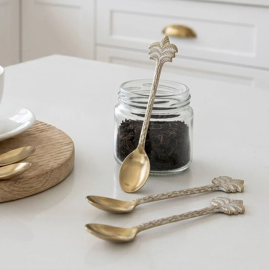 Decorative spoons with leaf designs on a kitchen counter next to a jar of dark food.