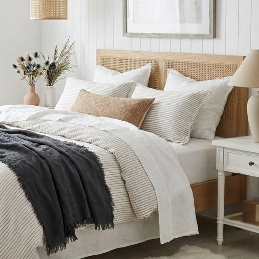 Neatly made bed with white bedding and a wooden headboard in a bedroom setting.
