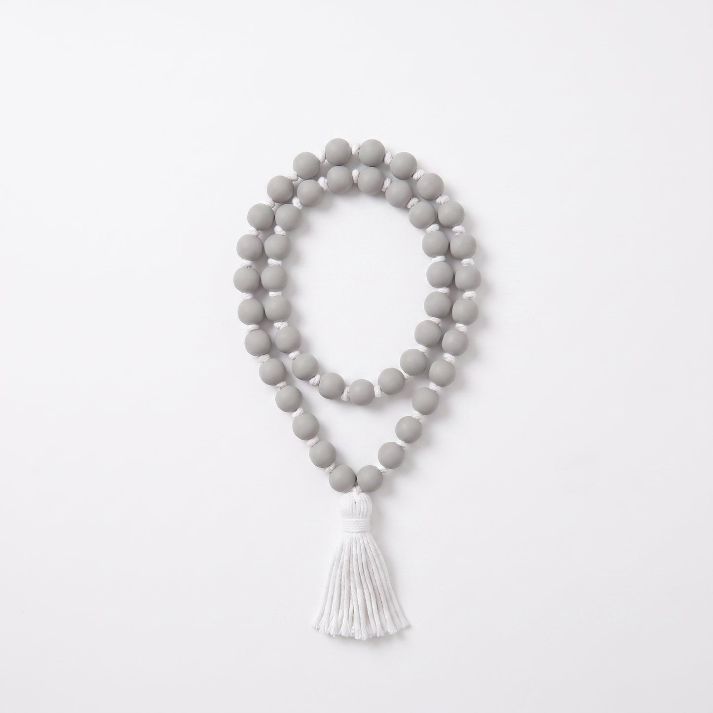 A double-strand beaded necklace with matte gray round beads and a white tassel, displayed on a clean white background.