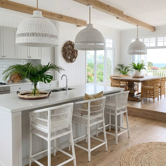 Modern kitchen with white island, stools, and pendant lights with a view of a garden.