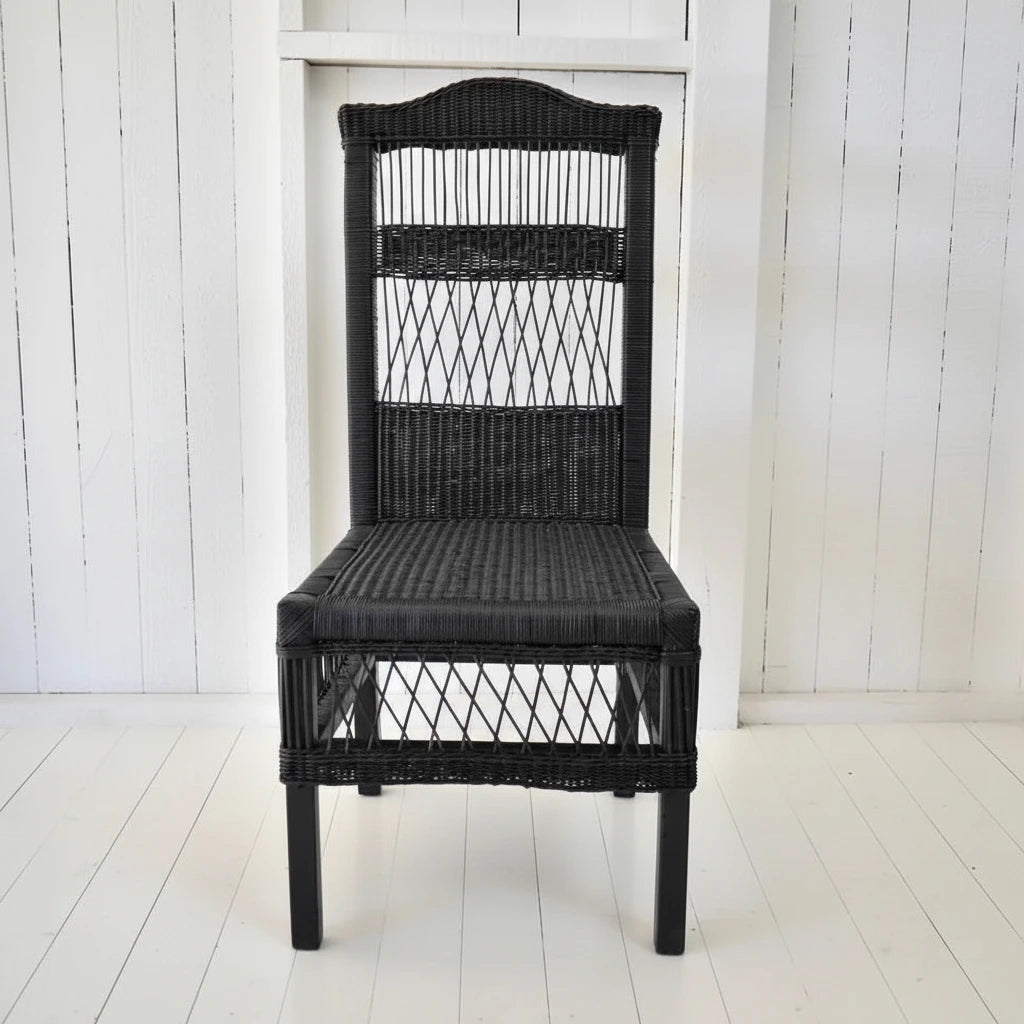 Black wicker chair next to a potted plant on a white wooden floor.