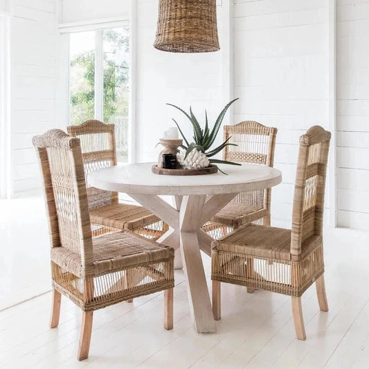 Dining area with round table and wicker chairs in a bright room.