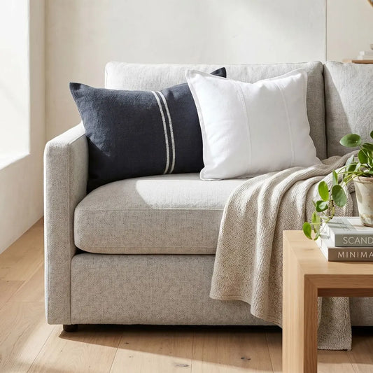 Gray sofa with decorative pillows and a blanket in a living room setting.