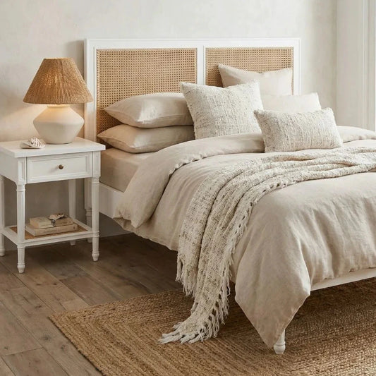 Neatly made bed with beige bedding in a bedroom setting.
