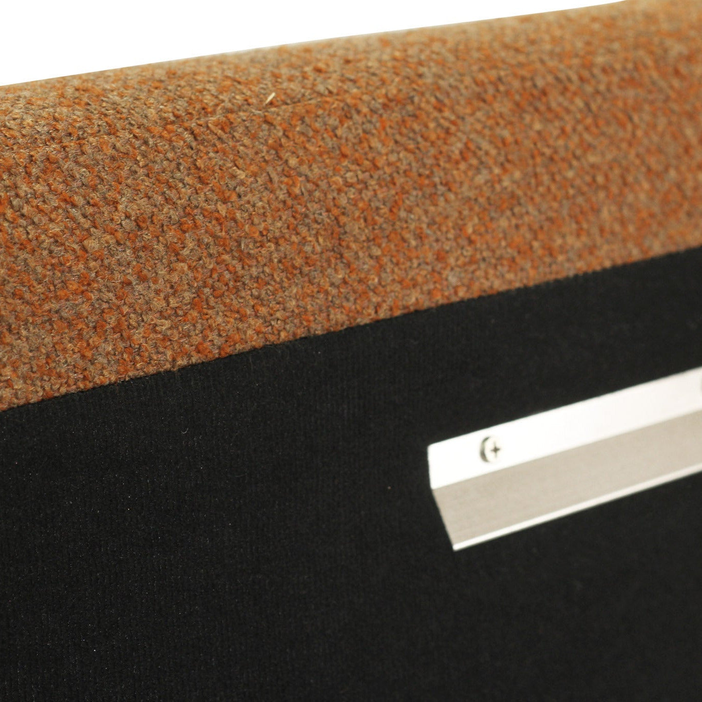 Close-up of a textured orange-brown carpeted surface above a black panel with a silver metal mounting strip.