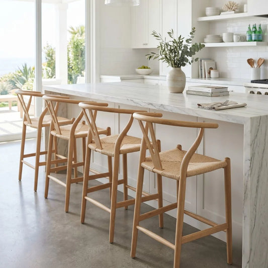Wooden bar stools in a modern kitchen with marble island and white cabinets.