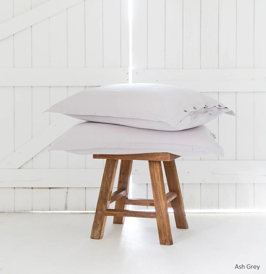 Ash Grey pillows on a wooden stool against a white paneled wall.