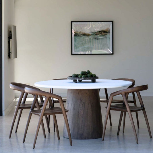 Dining room with a round wooden table and four chairs, featuring a framed picture on the wall.
