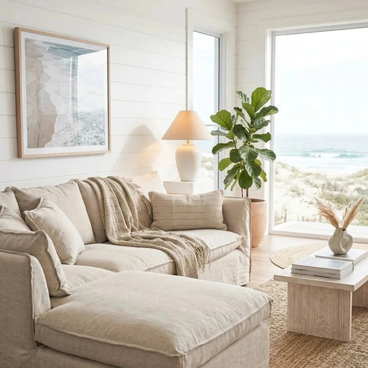 Cozy living room with beige sectional sofa, ottoman, and large windows overlooking a scenic view.