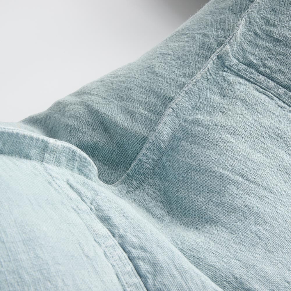 Close-up of light blue linen fabric with visible stitching and creases.