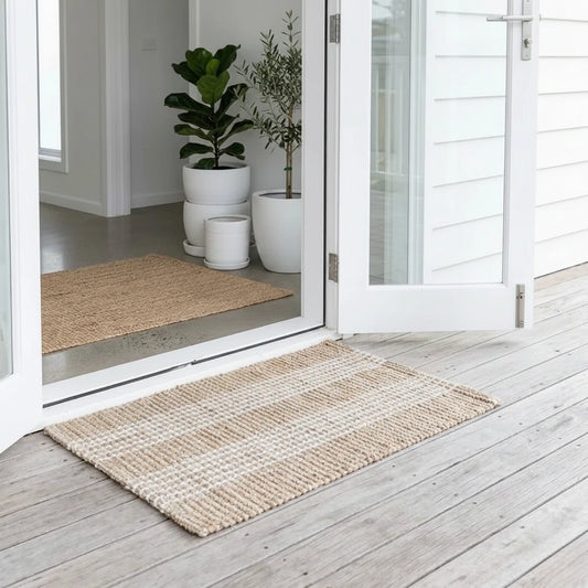 Natural woven mat on a wooden deck with plants and stones in the background