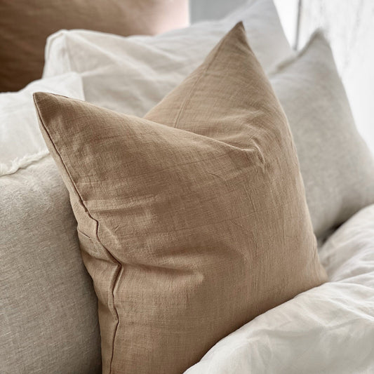 Beige pillow on a bed with white bedding