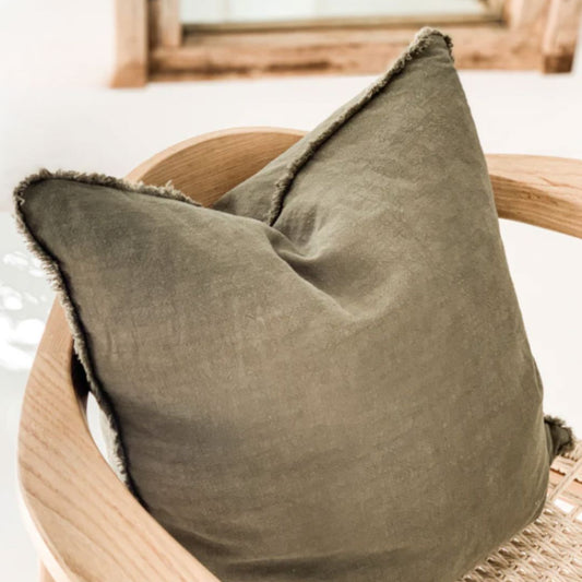 Olive Green pillow on a wooden chair with a blurred background