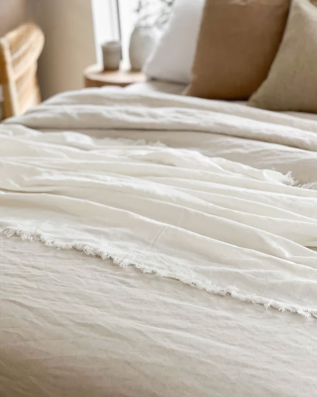 Close-up of a textured white blanket on a bed in a softly lit bedroom.