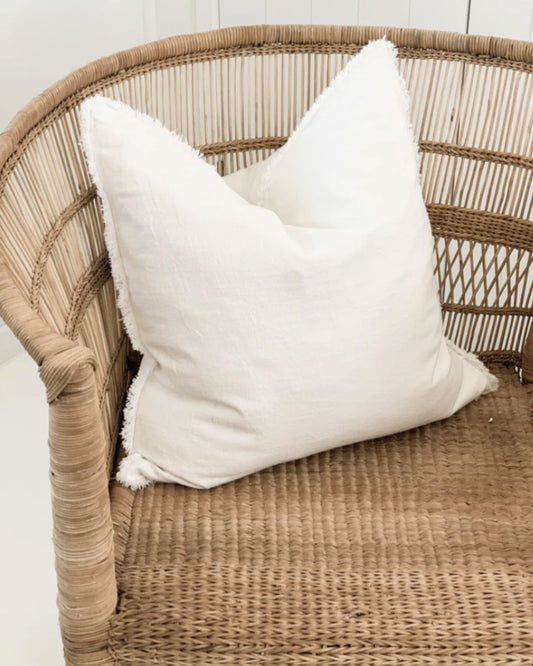 White pillow on a wicker chair with a white wall background