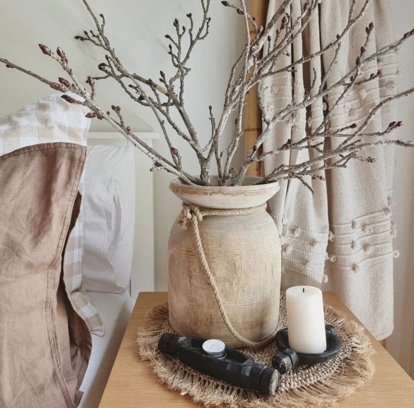 Decorative vase with branches and candle on a wooden surface