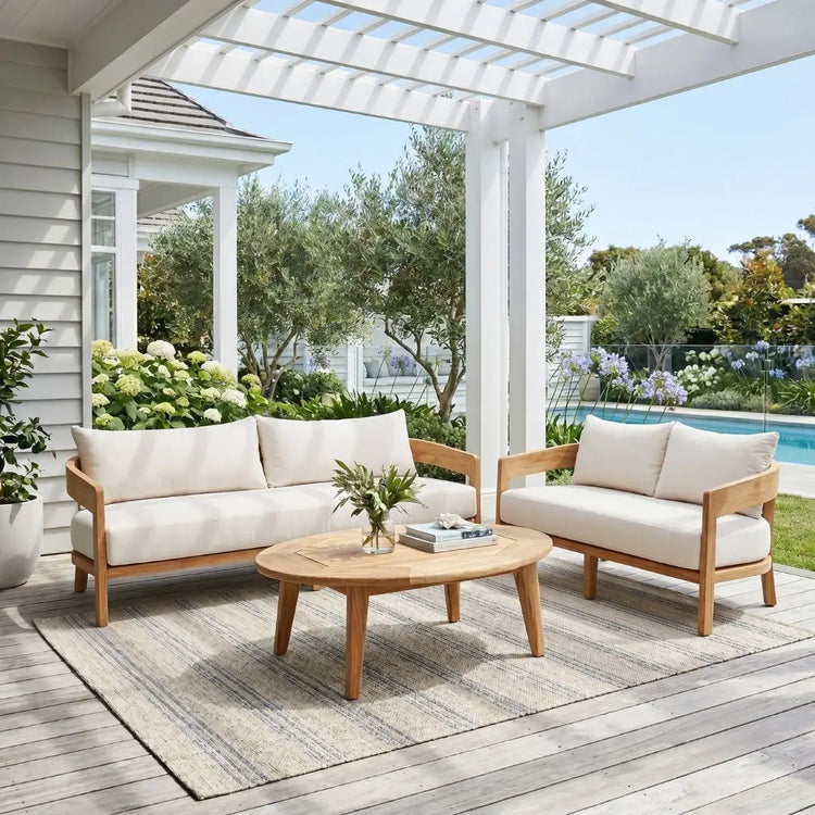 Outdoor patio set with white cushions on a wooden deck, featuring a sofa and two chairs with a coffee table.