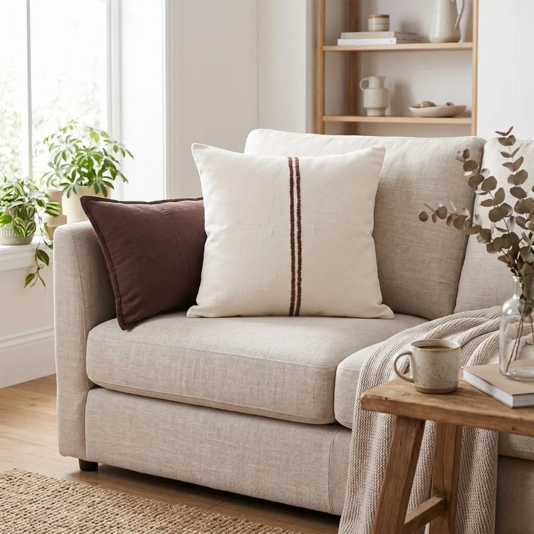 Beige sofa with decorative pillows and a wooden side table in a living room setting.