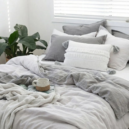 Neatly made bed with gray and white bedding in a bright room.