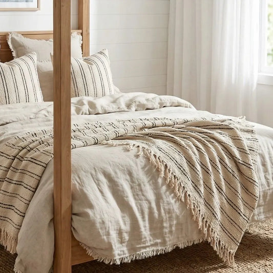 Bed with striped bedding and a wooden headboard in a bright room.