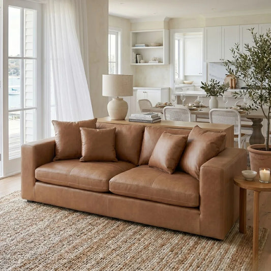 Brown leather sofa in a living room with a lamp, books, and decorative items.